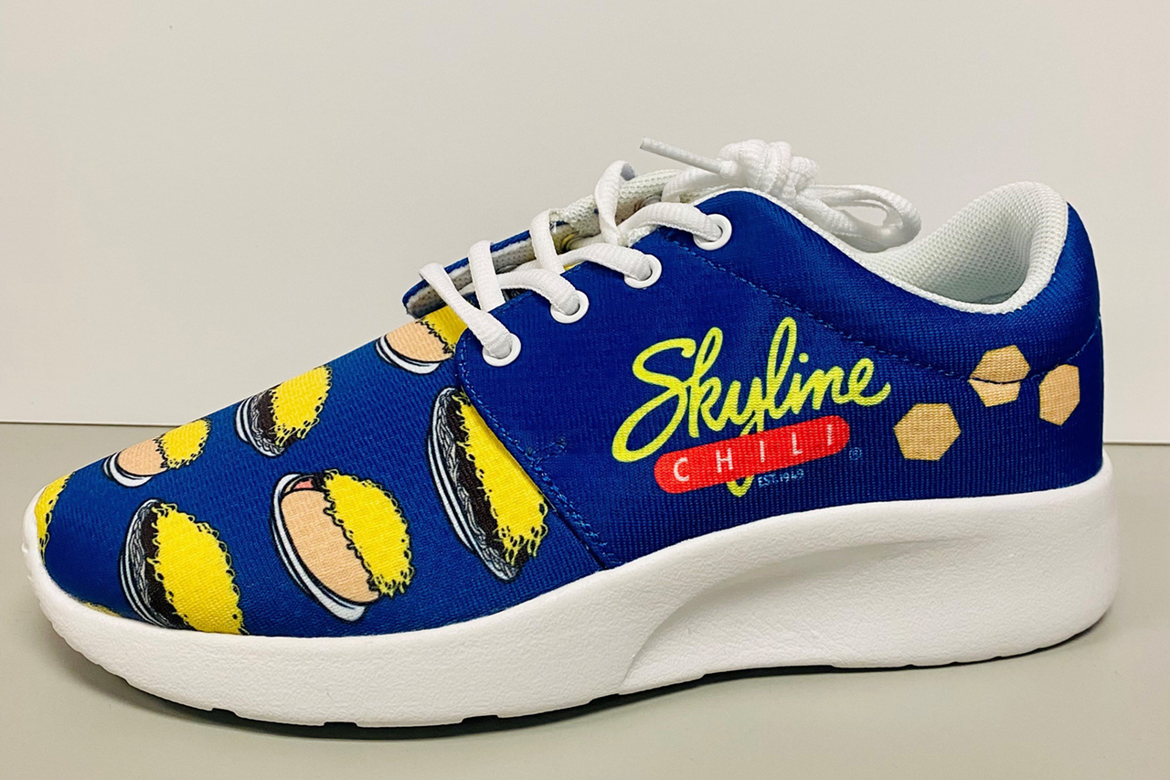 Skyline Released a Limited Run of Chili Sneakers
In July, Skyline Chili celebrated National Chili Dog Day by releasing a limited amount of branded sneakers. The local chili chain held a sweepstakes to give away 100 sneakers to fans who wanted to represent Skyline in every step of their lives. And because the sweepstakes was so successful, Skyline decided to make the shoes available for purchase for a limited time. The sneakers, which feature a blue background and illustrations of 3-Ways, cheese coneys and the Skyline logo, shipped in October.