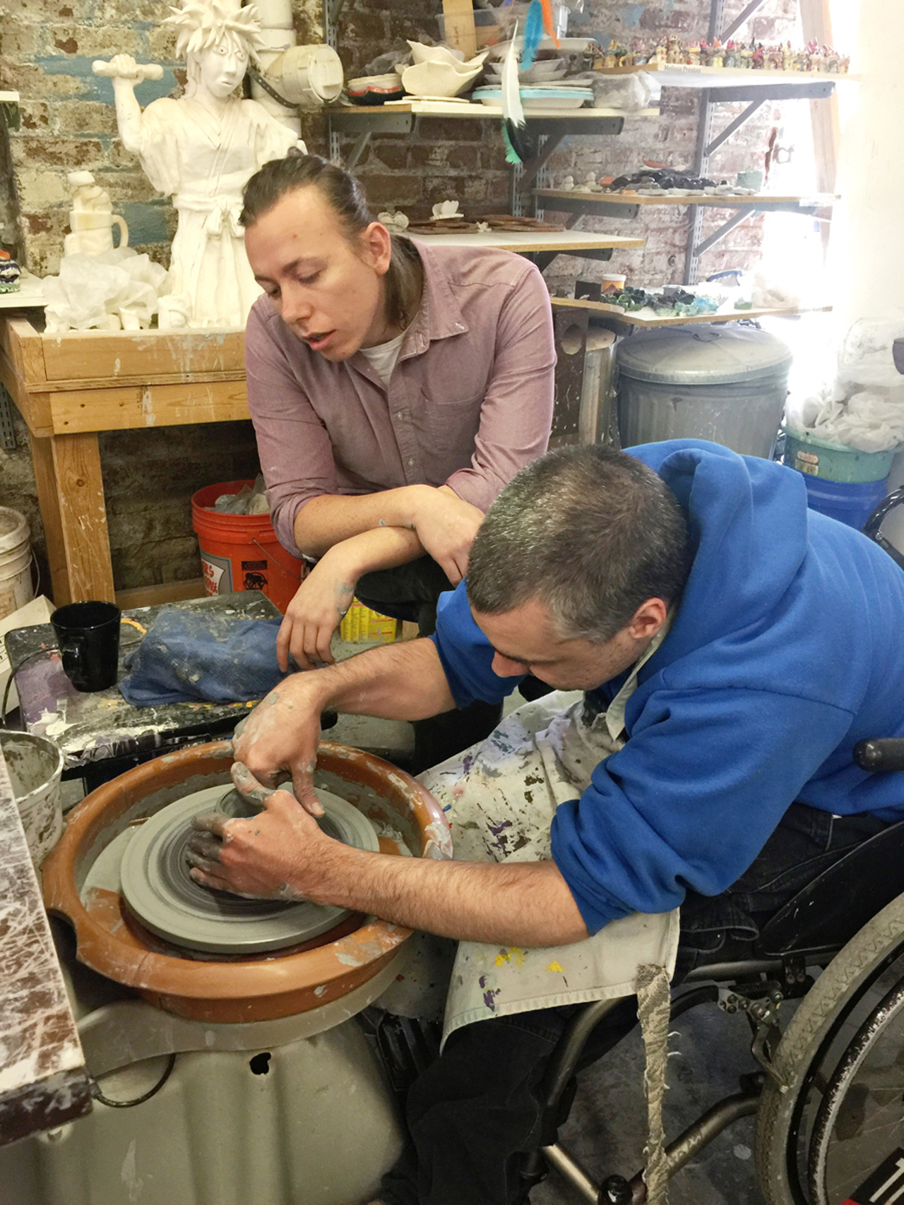 Nick Kraft uses clay wheel while James Dumstorf watches