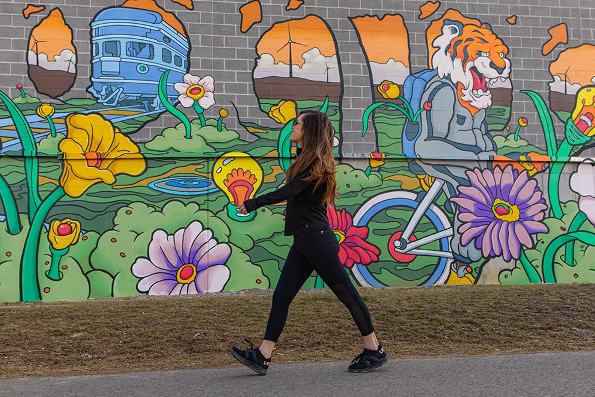 A walker passing by the Duke Energy complex's "Electric Avenue" mural on Wasson Way