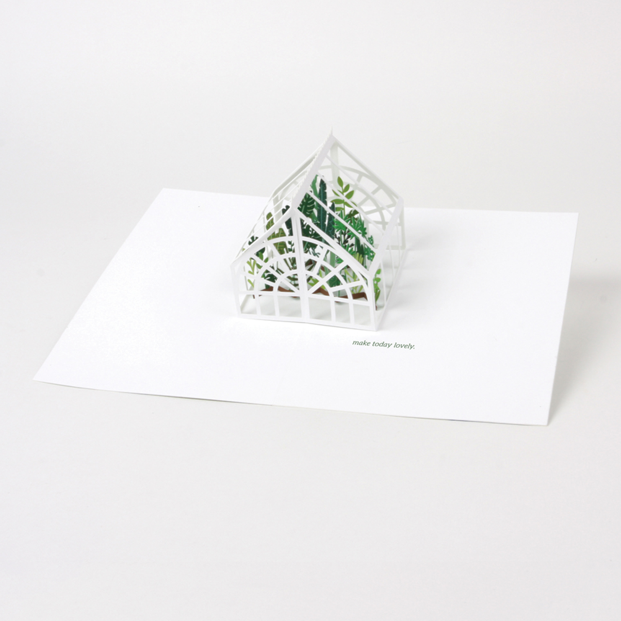 Laser cut leaves are nestled inside a cut greenhouse in this card.