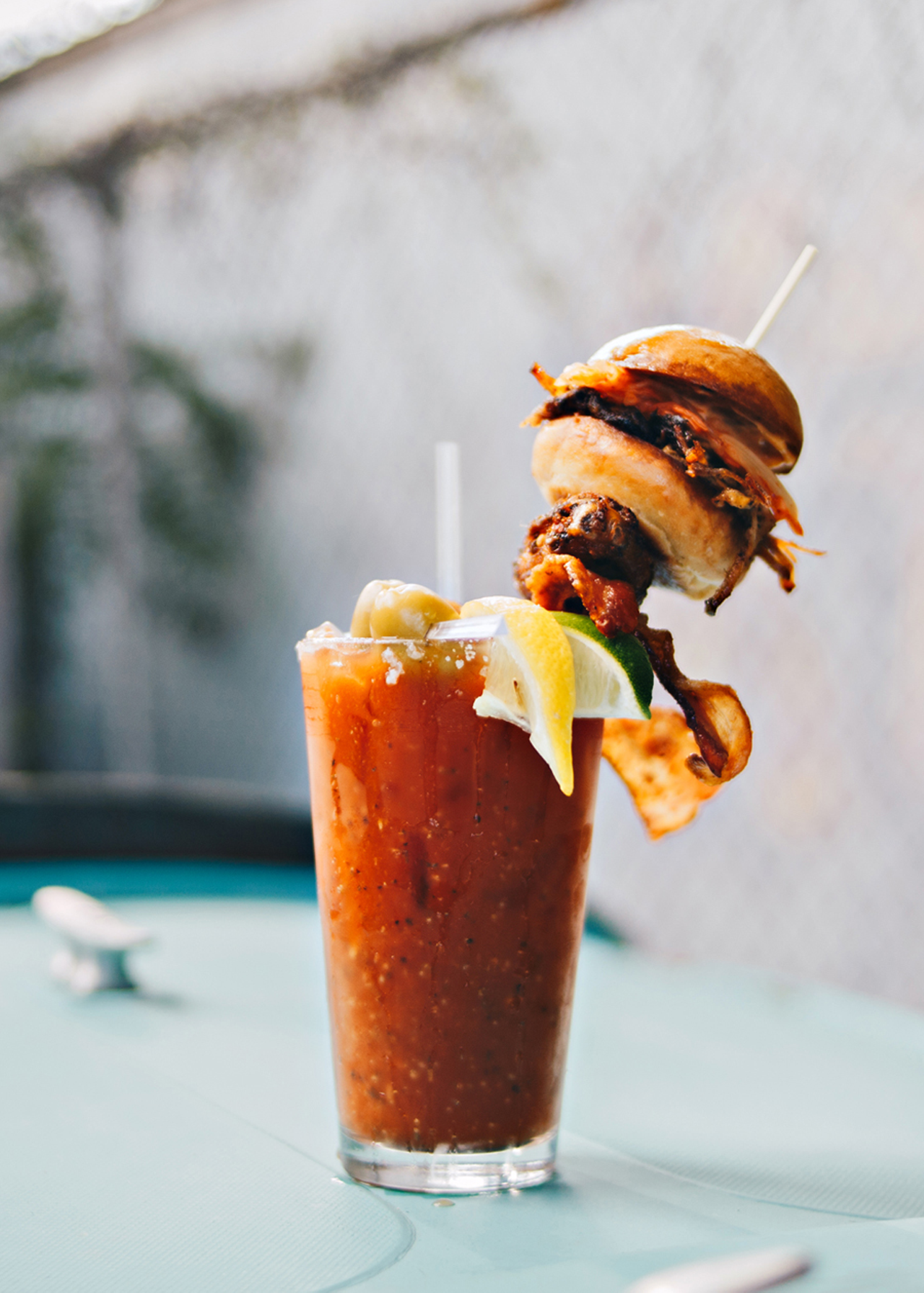 The Yacht Club Bloody from Northside Yacht Club is made with a secret homemade bloody mix (made fresh every Sunday) is infused with Tito’s vodka and citrus juices and then topped with an obscene smörgåsbord of meat: a house breakfast sausage slider, American hickory bacon, a house-smoked Amish wing and a piece of celery for good measure. The mix is balanced — not spicy or salty — but there are hot sauces available if you want to kick it up a notch.