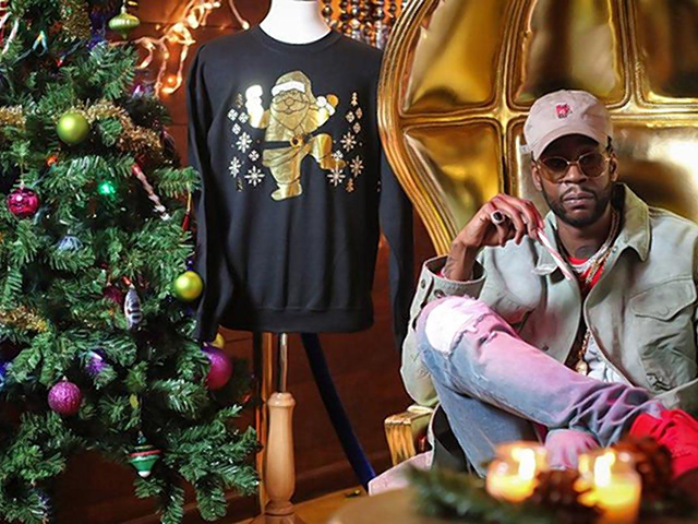 2 Chainz poses with the $90,000 Christmas sweater he's selling.