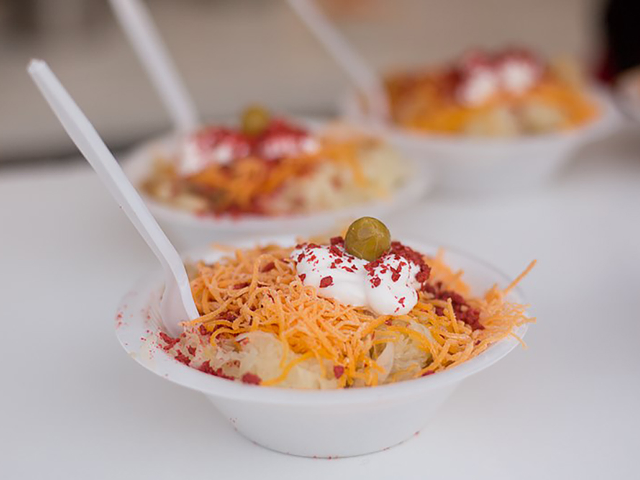 A "German sundae" — potatoes topped with cheese, bacon, sour cream, sauerkraut and a green olive