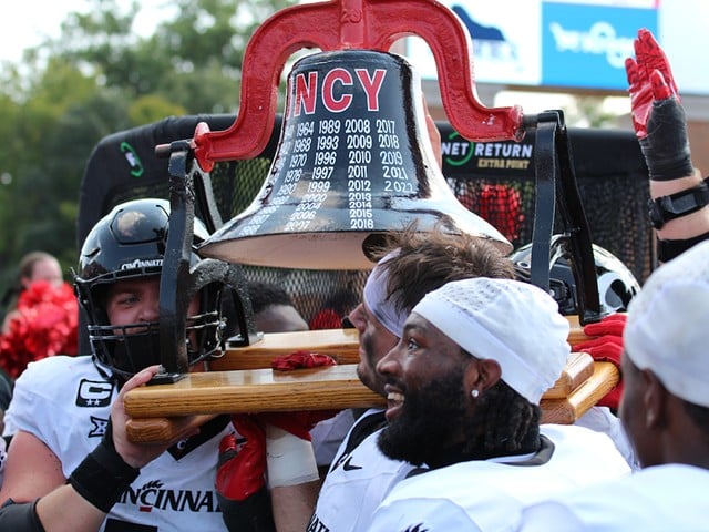 University of Cincinnati players carry the Victory Bell toward UC fans.