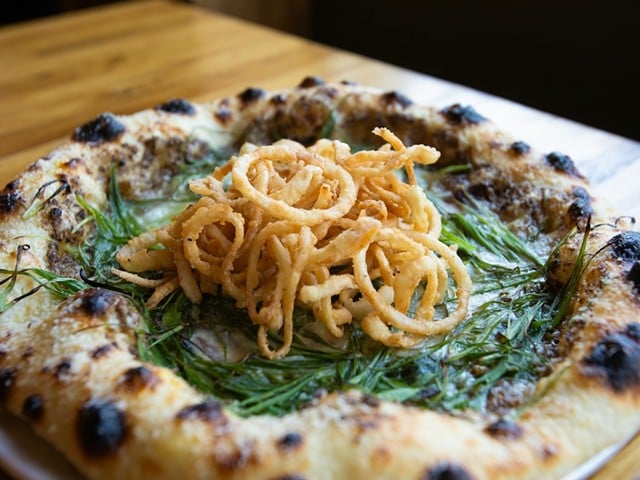 A pizza topped with crispy onions from Companion