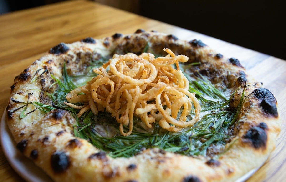 A pizza topped with crispy onions from Companion