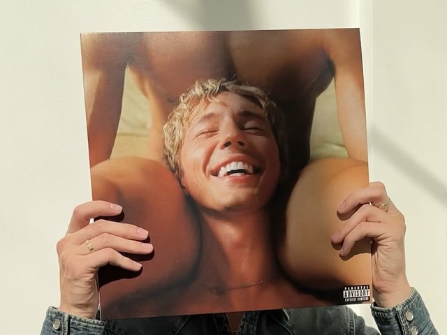 Troye Sivan holding his new record, Something To Give Each Other
