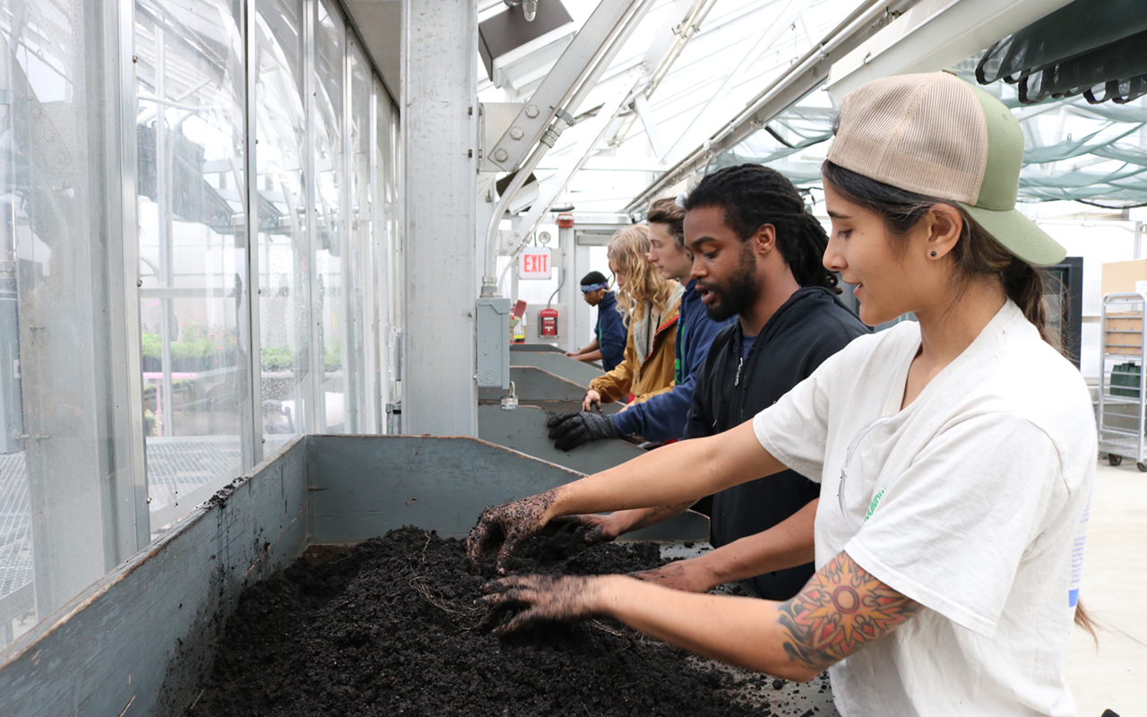 Green Corps members prepare soil for seeding at a community greenhouse. The oak trees and milkweed grown with this soil will either be used to provide sites like Little Duck Creek with native plants or sold to interested buyers.
