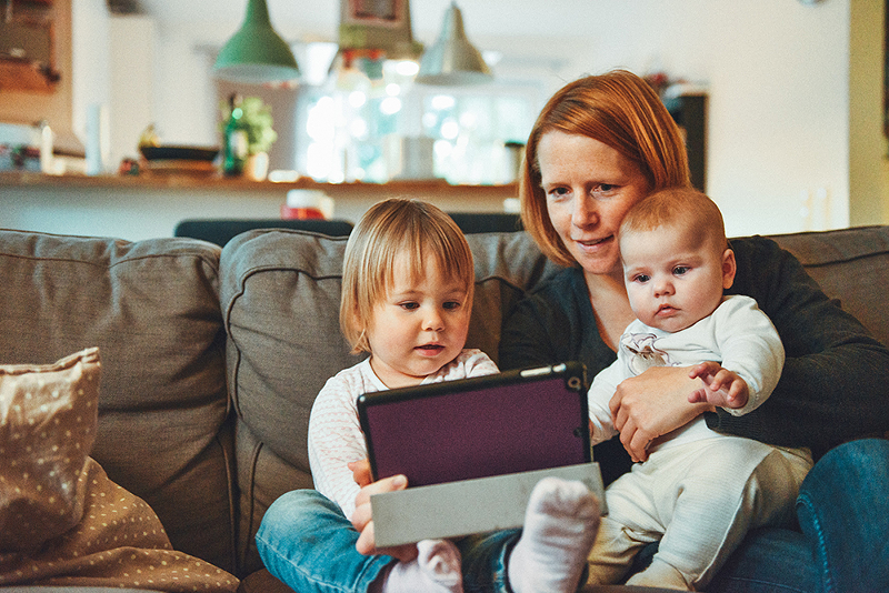 A mother holding two small children and an iPad - PHOTO: ALEXANDER DUMMER