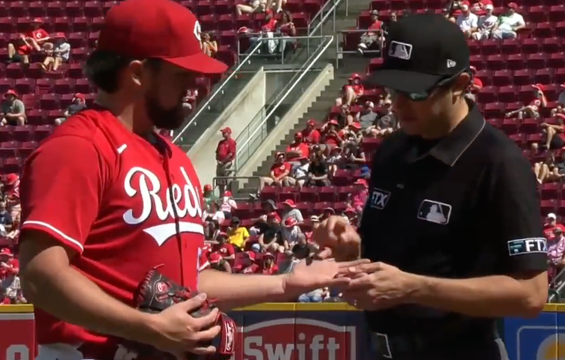 An umpire inspects the hand of Cincinnati Reds pitcher Graham Ashcraft on June 18, 2022. - Photo: video still via twitter.com/atbbttr