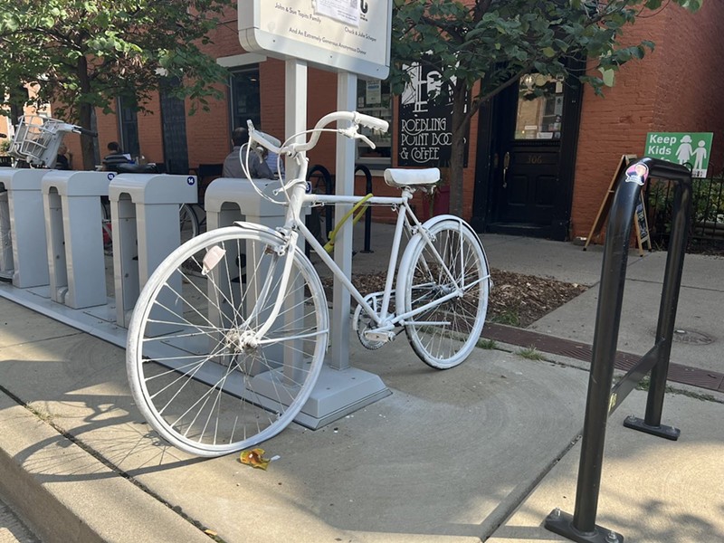 A "ghost bike" sits outside of Roebling Point Books and Coffee where Gloria San Miguel worked. The white painted bikes are a symbolic memorial for cyclists who are killed while riding. - Photo: Madeline Fening
