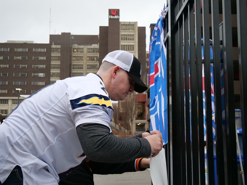 Brandon Metzger works to fix signs of support for Buffalo Bills’ safety Damar Hamlin outside UC Medical Center on Jan. 3. - Photo: Madeline Fening